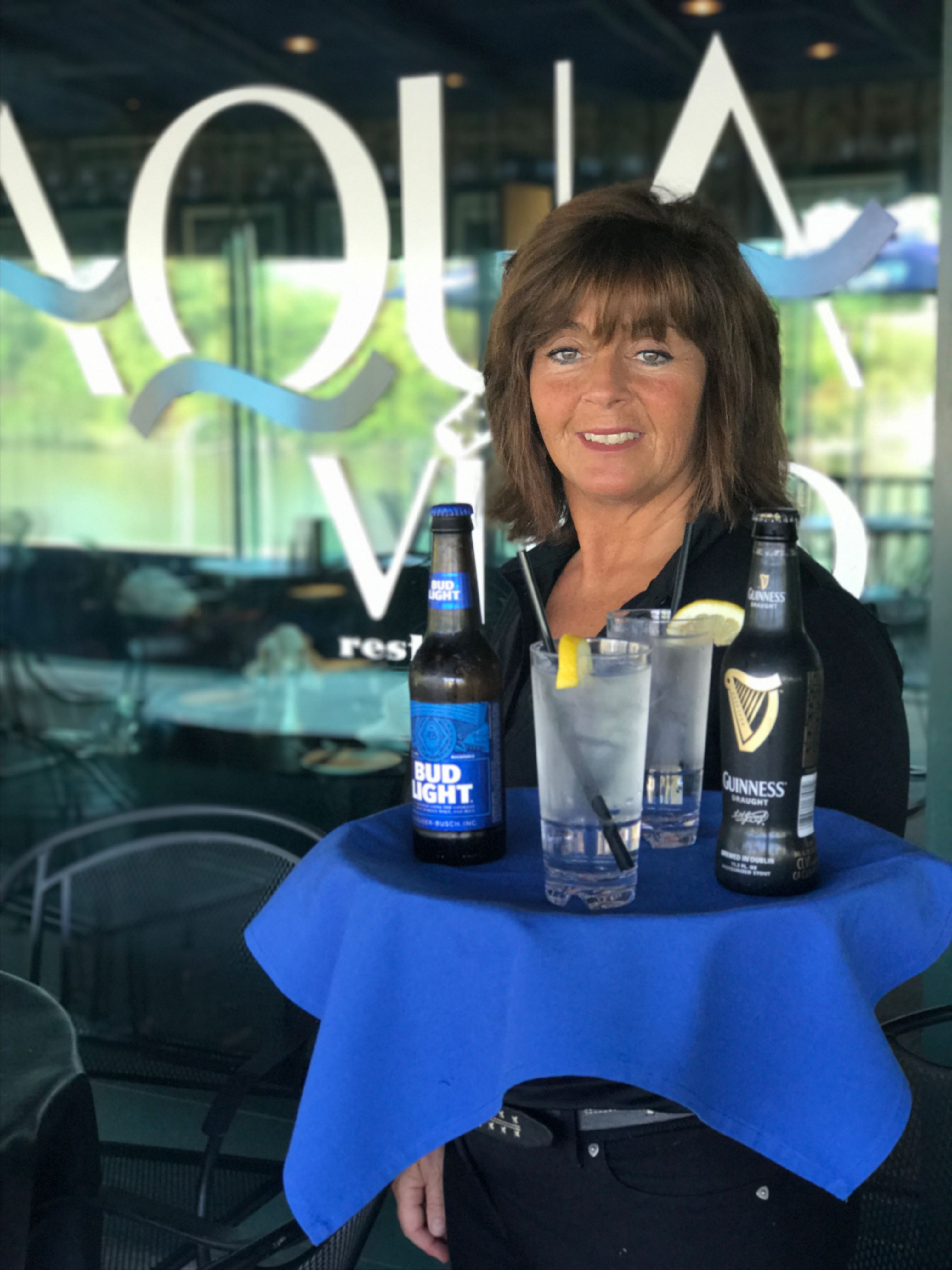 trish holding tray of beer bottles and glasses filled with water